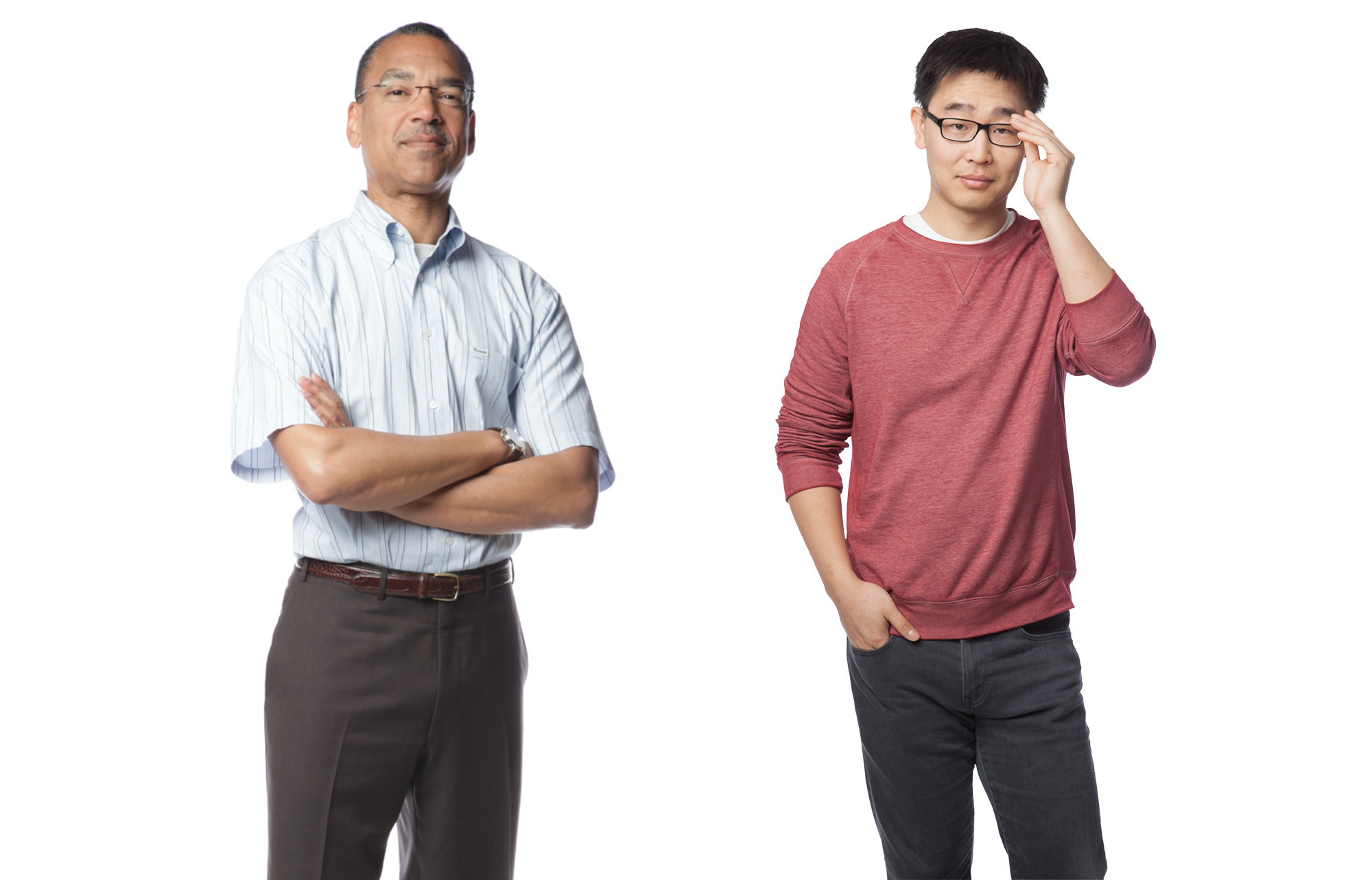 Portrait of two men. One, middle aged, looks confidently at the camera. The younger Asian man adjusts his glasses.