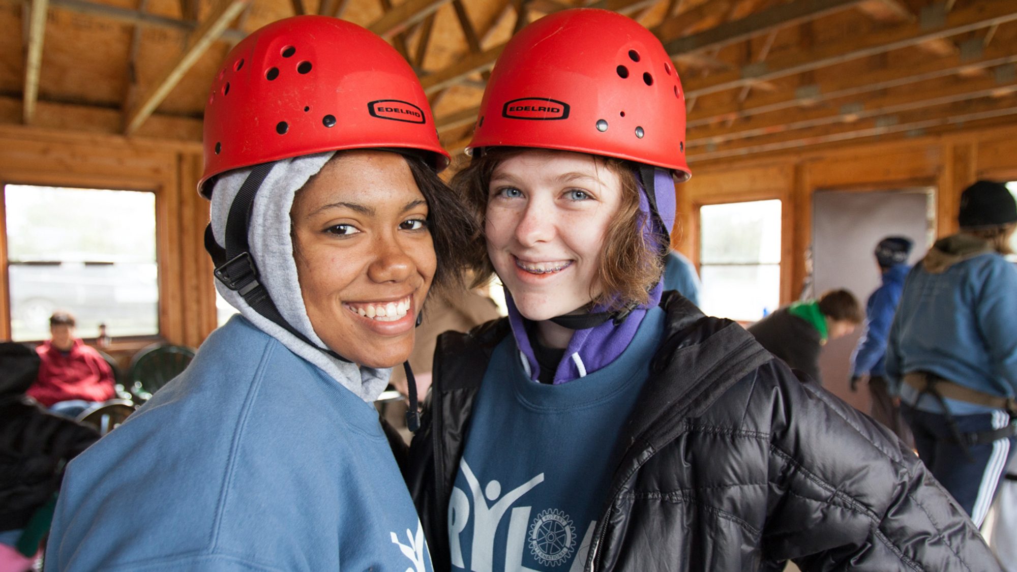 Two young women, one white one black, wearing hard hats and smiling toward the camera.
