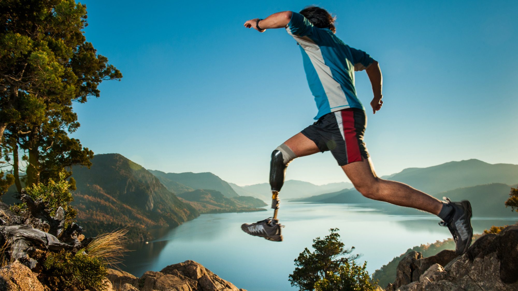 Man with a prosthetic leg running in a wild landscape.