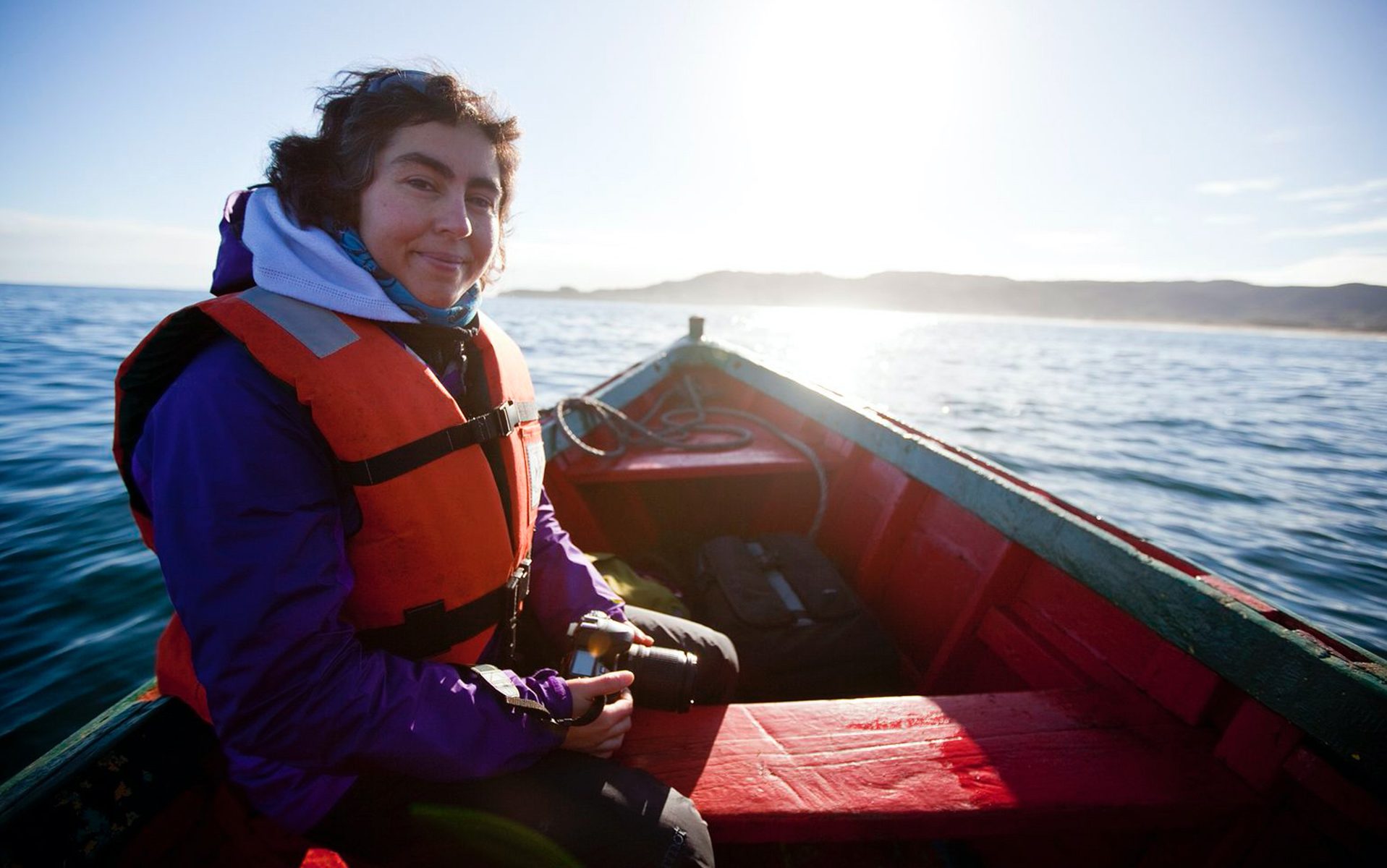 A woman in a small boat wearing a life jacket.