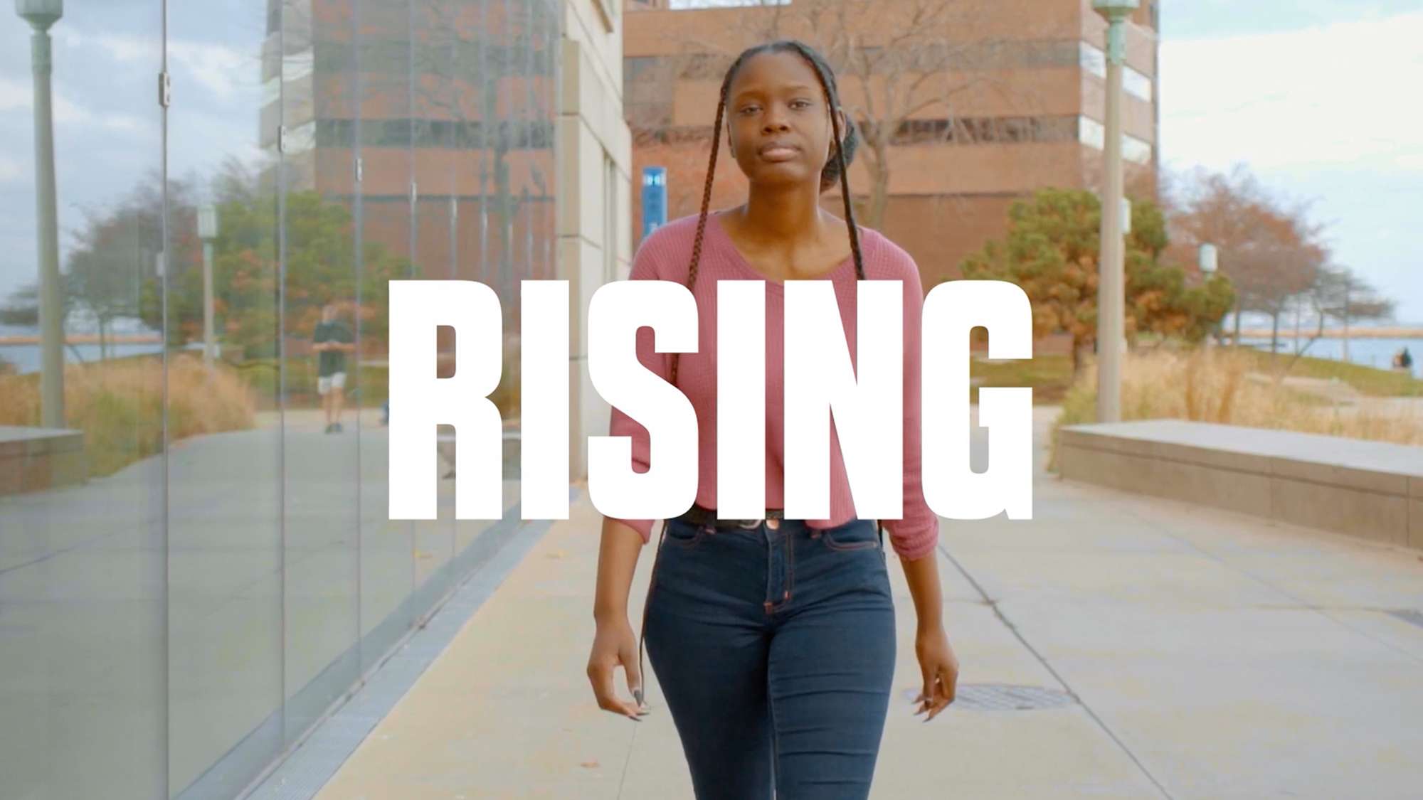 Video still — young black woman walking toward the camera.