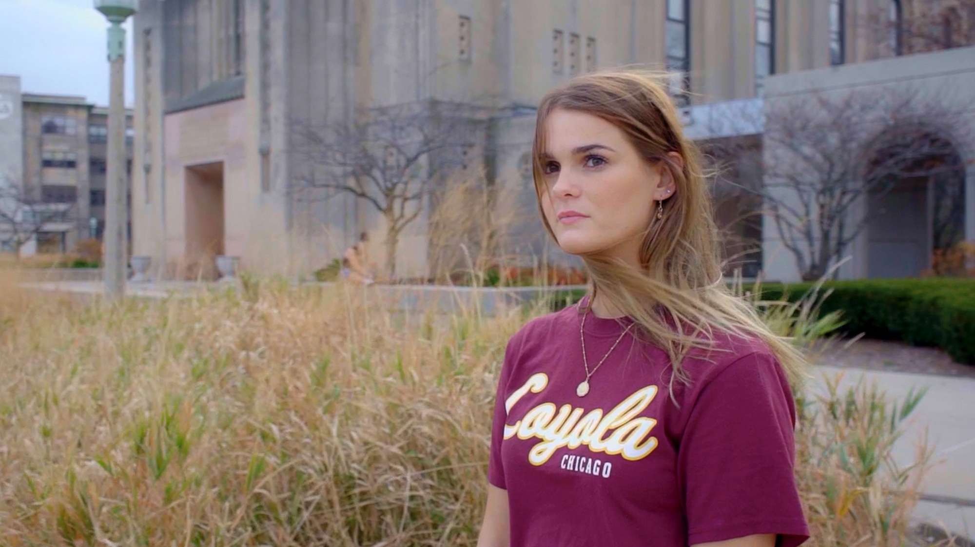 Video still — college age white woman in red Loyola tee shirt.