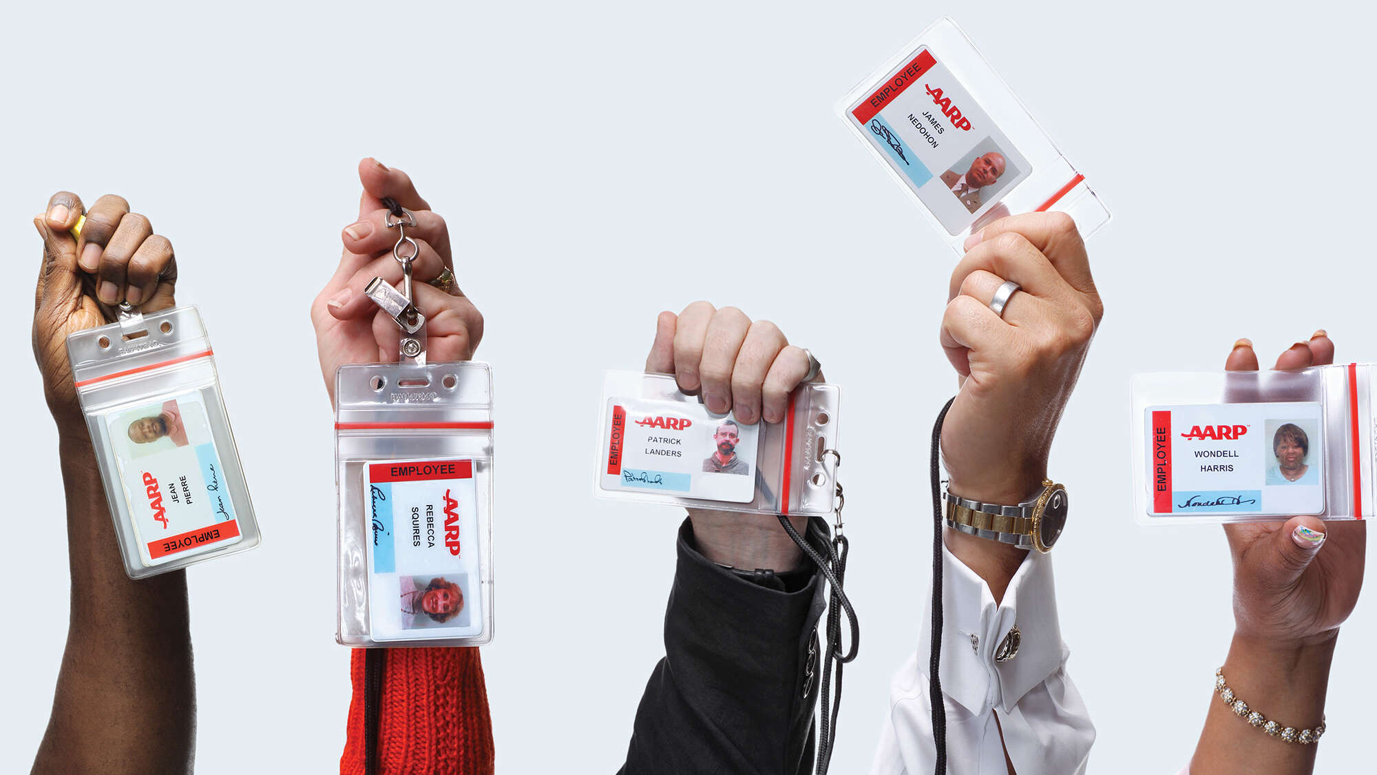 5 hands holding up lanyards with AARP ID cards